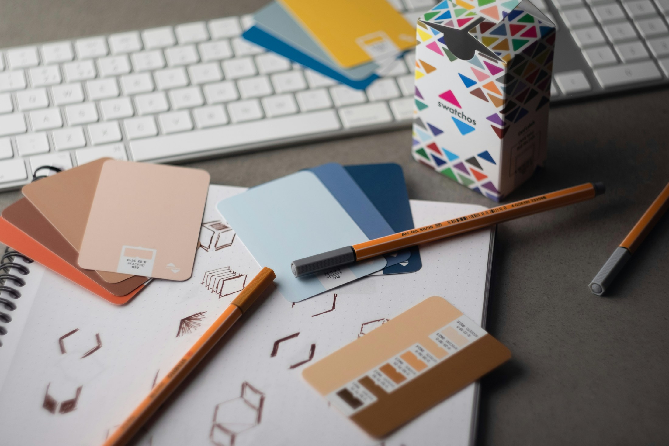 Color swatches, pens and logo sketches on a design desk